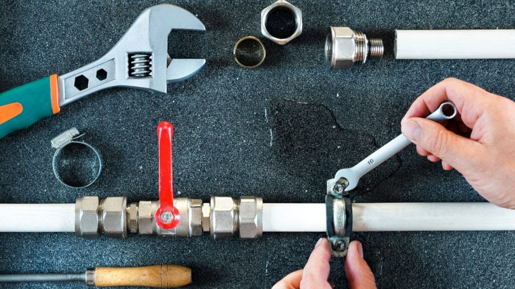 Plumber repairing a pipe valve with an adjustable wrench in Lafayette