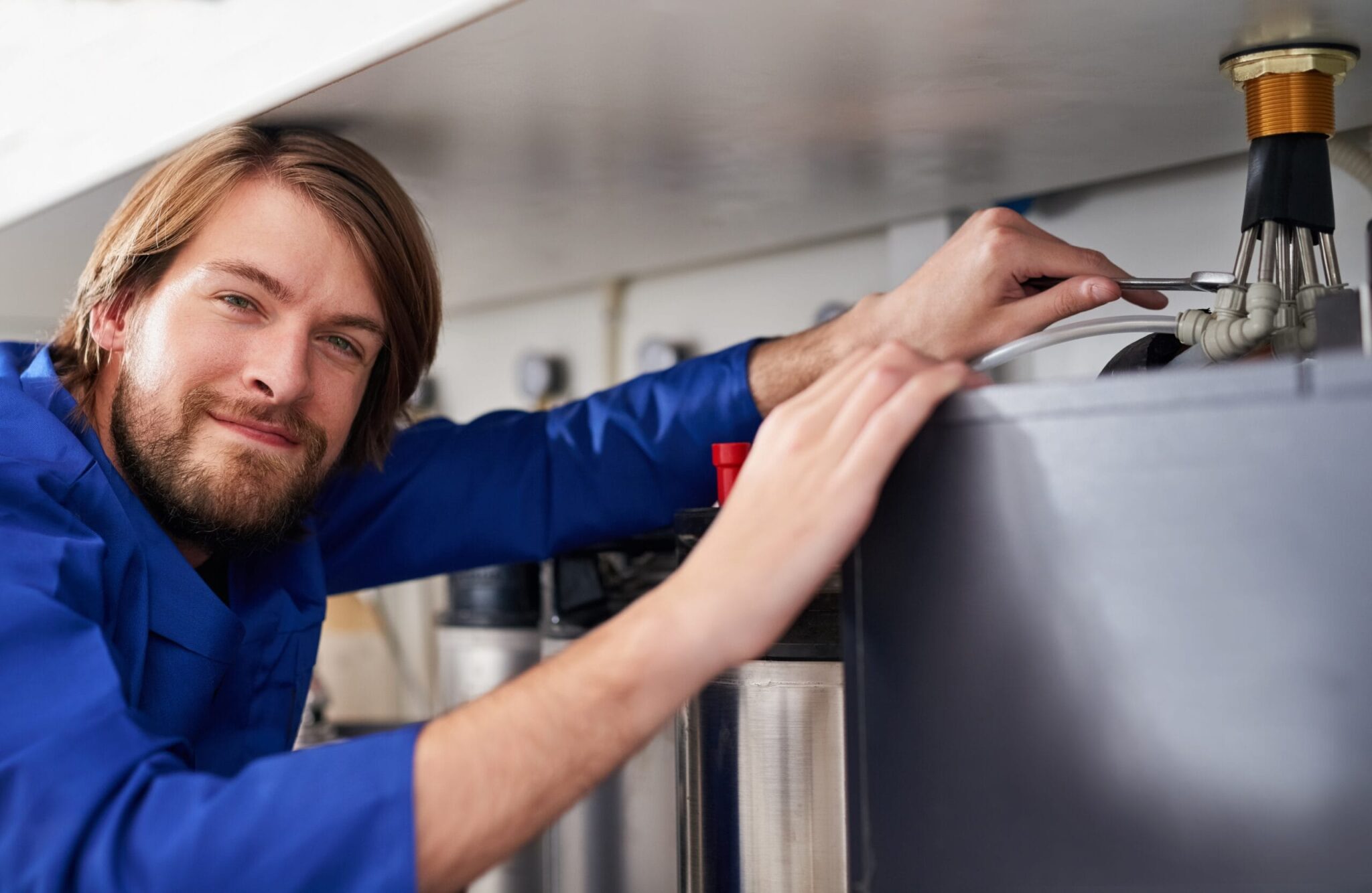 Technician servicing a residential water heater tank in Lafayette