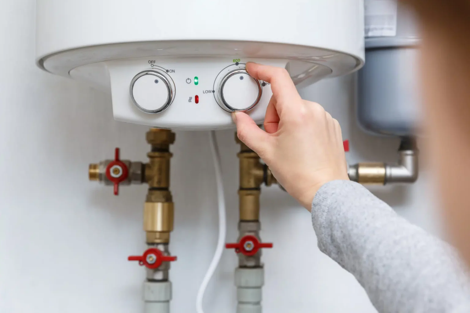 Homeowner adjusting the temperature controls on a water heater in Lafayette